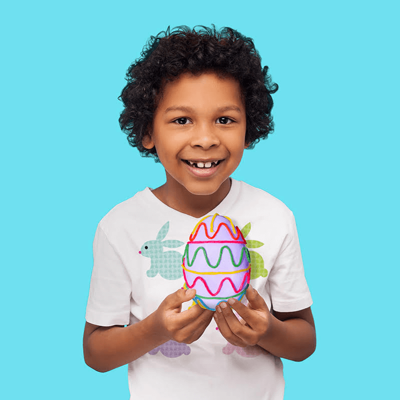 Boy holding a plastic egg decorated with Wikki Stix.